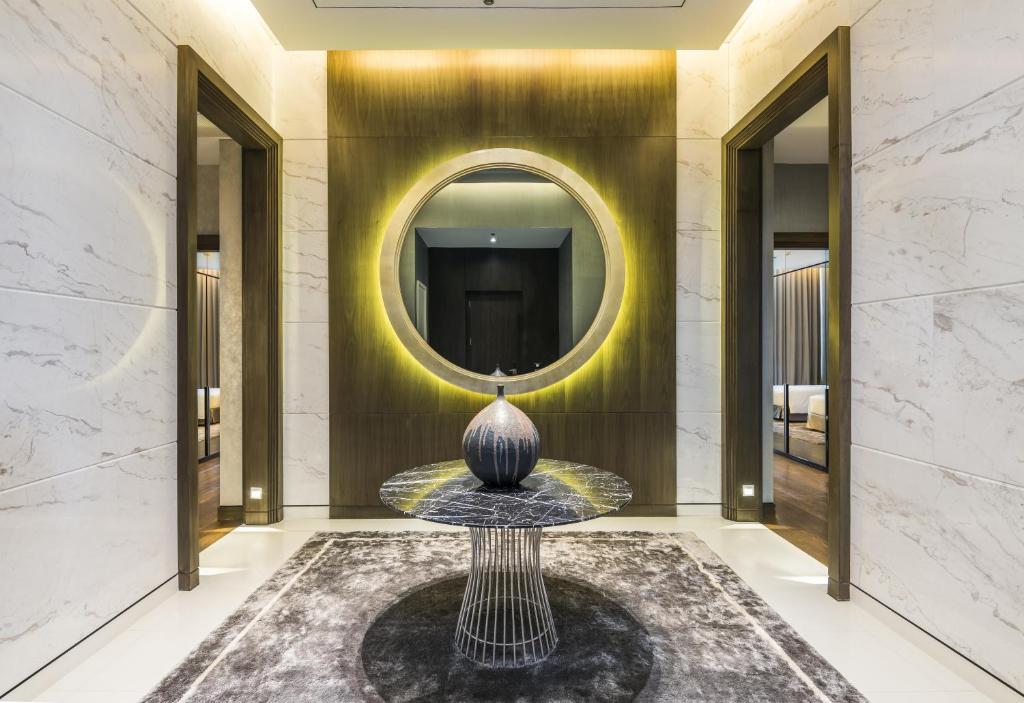 An elegant marble-lined entrance or lobby alcove with a lit round mirror.