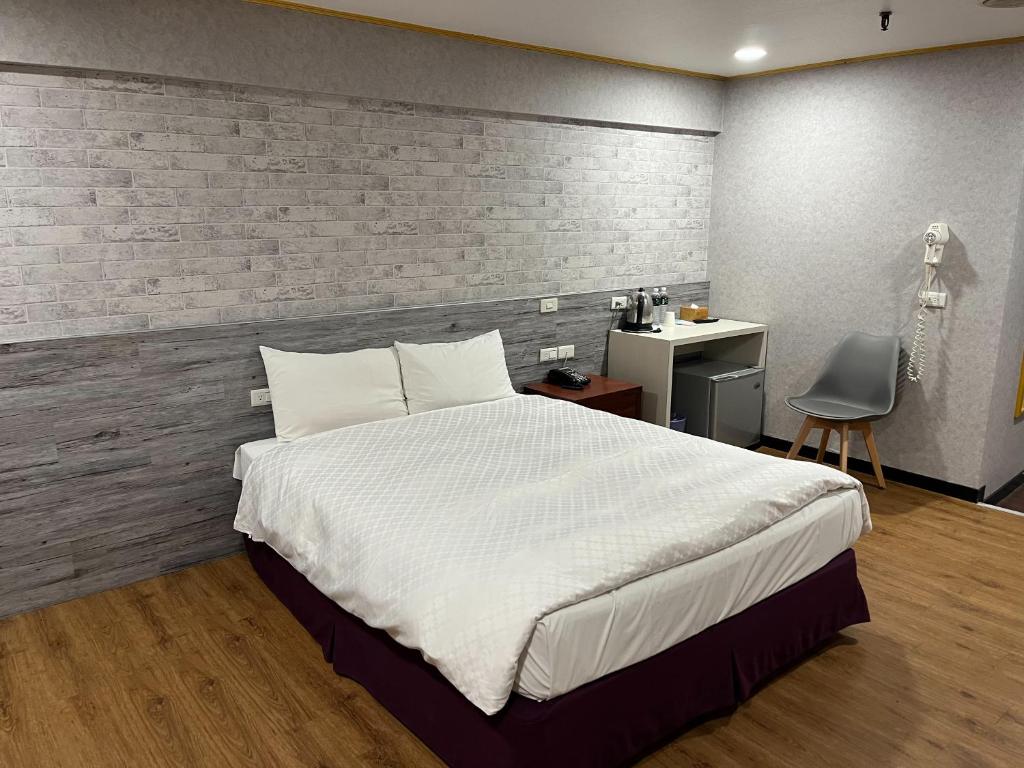 a bedroom with a large white bed and a desk at Tie Dao Hotel in Tainan