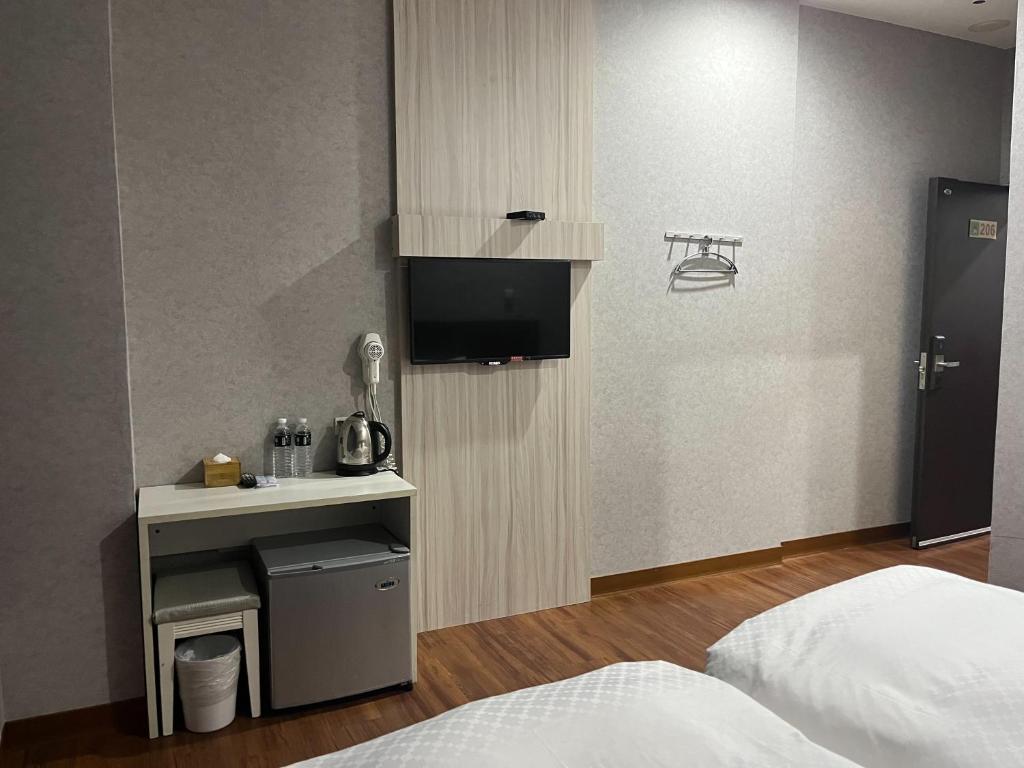 a hotel room with a bed and a tv in a room at Tie Dao Hotel in Tainan