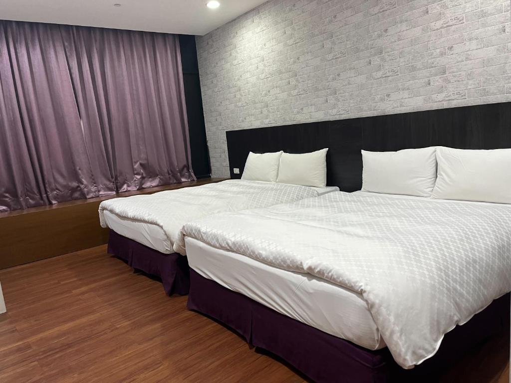 a bedroom with two beds and a brick wall at Tie Dao Hotel in Tainan