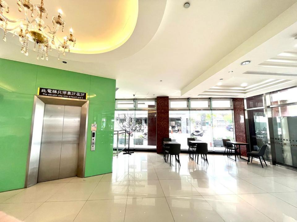 a lobby with a green wall and tables and chairs at Tie Dao Hotel in Tainan