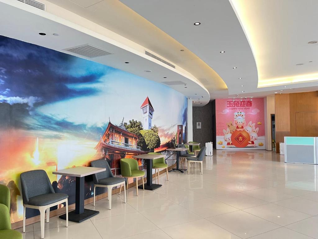 a lobby with tables and chairs and a large mural at Tie Dao Hotel in Tainan