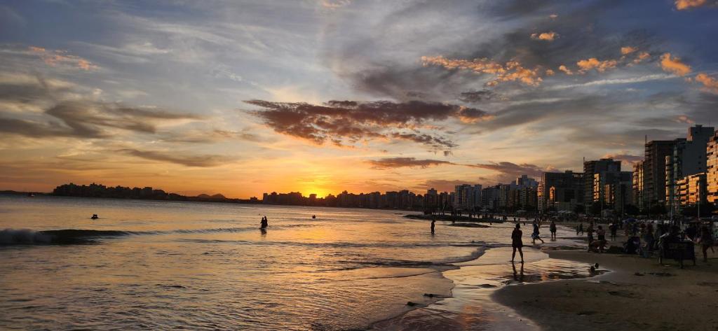 een groep mensen op het strand bij zonsondergang bij Apartamento Quartos Vista Praia do Morro Casais Melhor Localização, Super Completo 4 TVs Led, Camas-box Novas, 2 Quartos Suíte, Garagem, 2 Ar Condicionados, Wifi 300mb, Varanda Gourmet, Cervejeira, Novo para Famílias in Guarapari