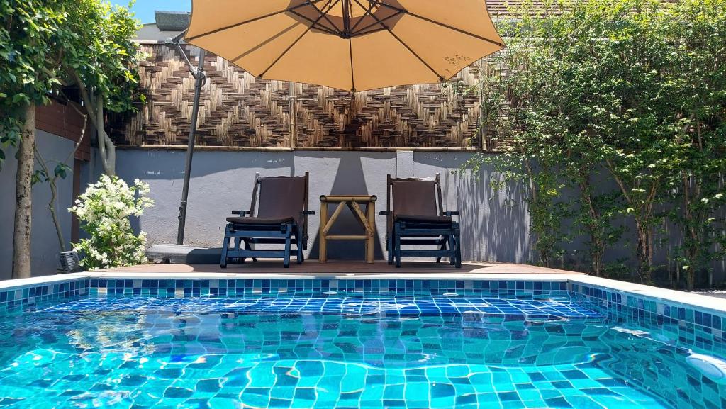 a swimming pool with two chairs and an umbrella at Ton Yaang private pool villa in Ao Nang Beach