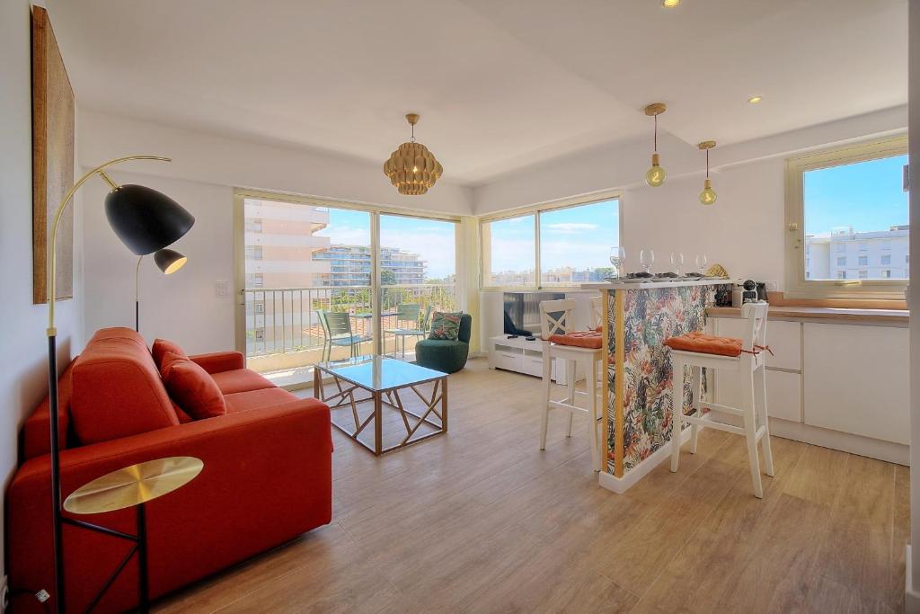 un salon avec un canapé rouge et une cuisine dans l'établissement IMMOGROOM - 5 min from the Croisette beaches - Terrace - Ac - Sea view, à Cannes