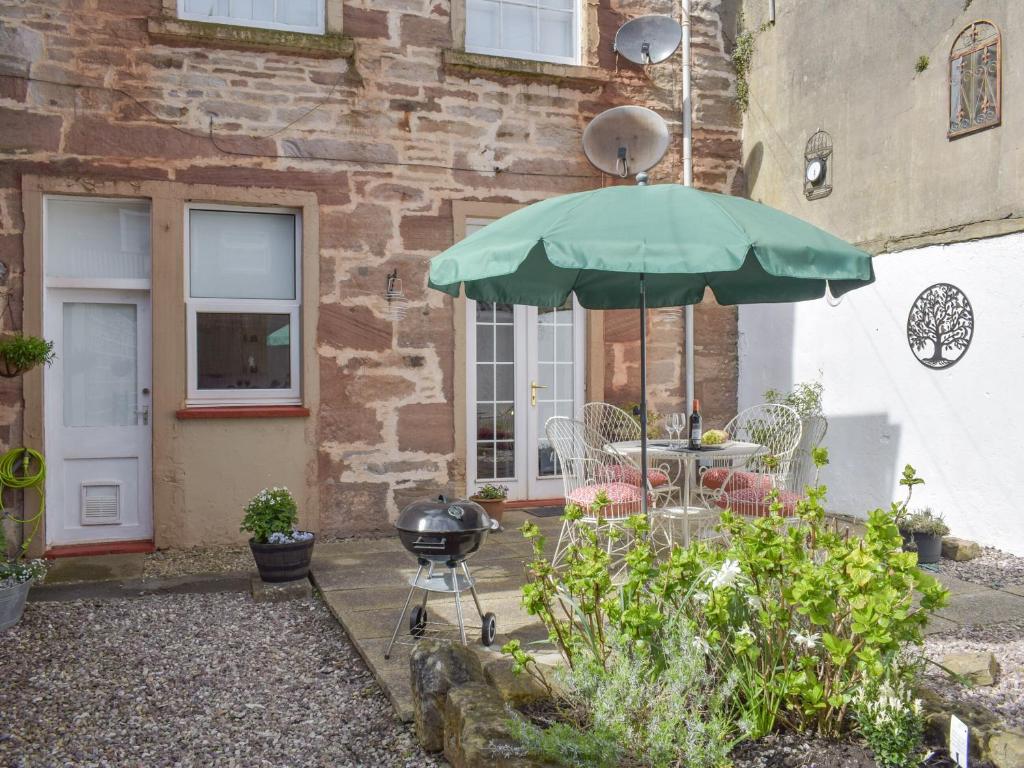 a patio with a grill and an umbrella at The Secret Garden in Ayr