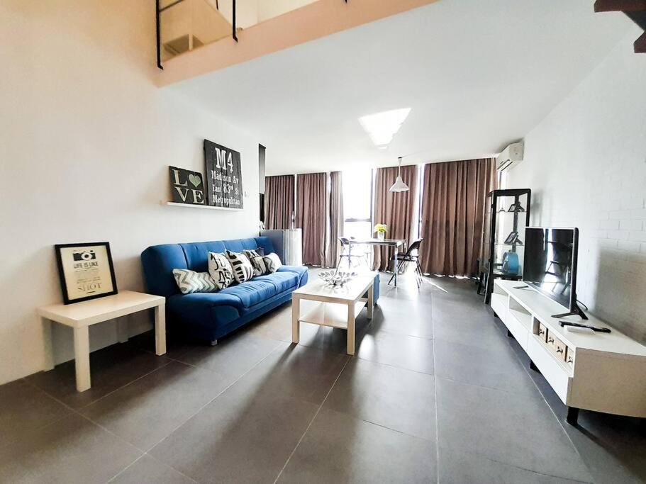 ein Wohnzimmer mit einem blauen Sofa und einem TV in der Unterkunft FREE Parking, 1-5 Pax Soho LOFT Empire Damansara in Petaling Jaya