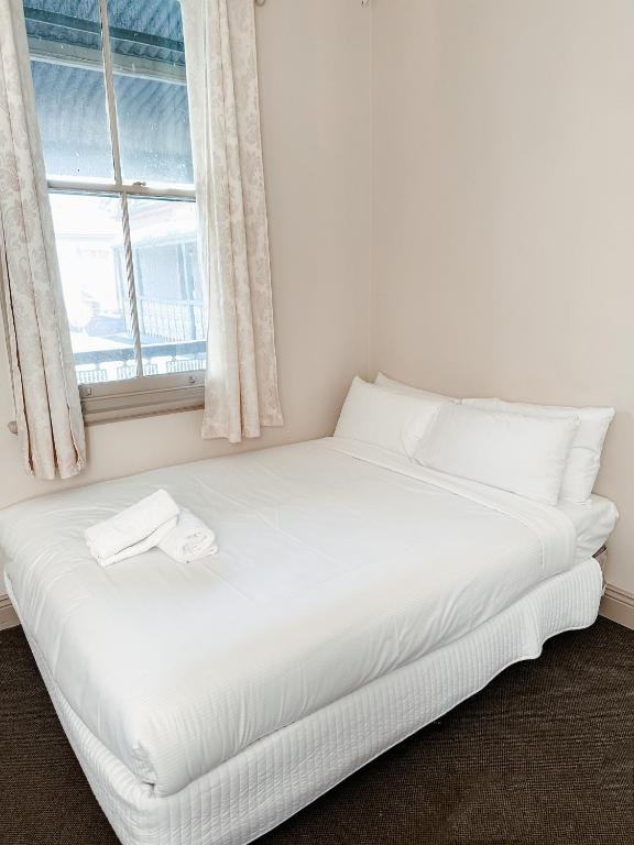 a white bed in a room with a window at Central Hotel Stroud in Stroud