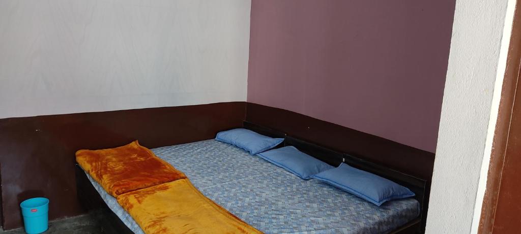 uma pequena cama com almofadas azuis num quarto em Gomukh Home Stay em Uttarkāshi