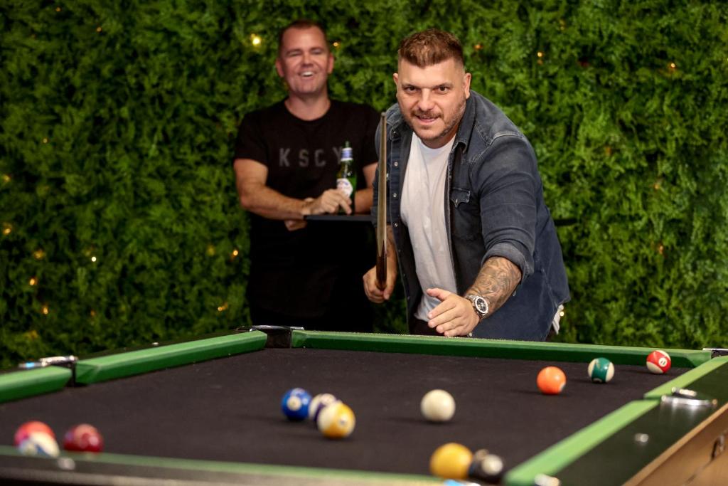 two men standing next to a pool table at Bayside House in Melbourne