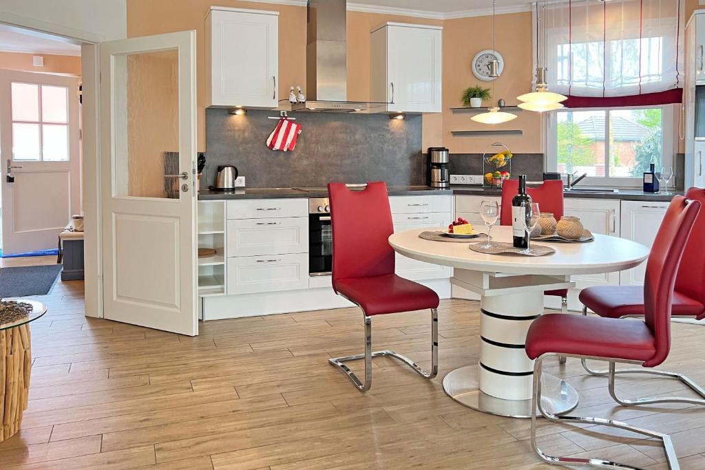 une cuisine avec des chaises rouges et une table blanche dans l'établissement Käptn ADI, à Groß Kirr