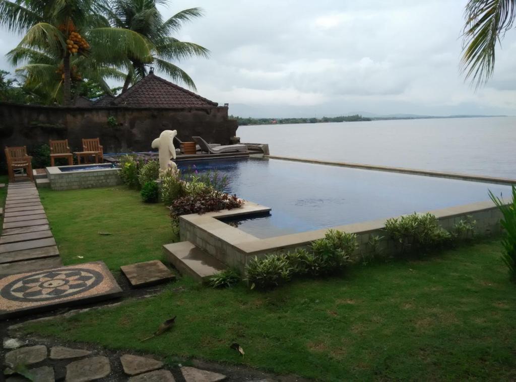 a swimming pool in a yard next to a body of water at Wahyu Dana Hotel in Lovina