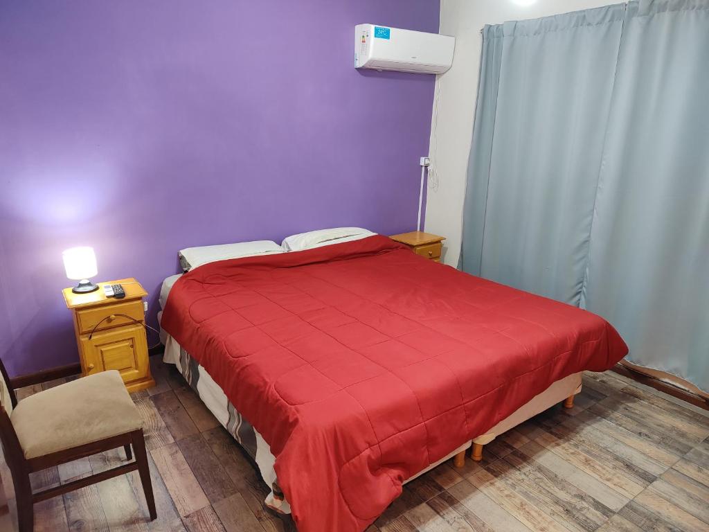 1 dormitorio con 1 cama roja y 1 silla en Máximo cdlu en Concepción del Uruguay
