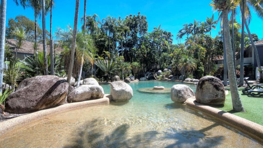 a pool in a resort with rocks in the water at 99 Reef Resort Port Douglas in Port Douglas