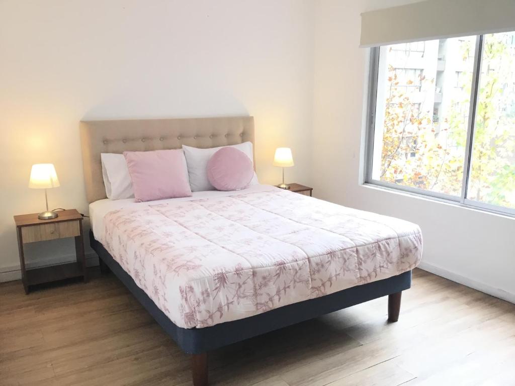 a bedroom with a bed with pink pillows and a window at Gran Departamento de tres dormitorios a pasos del metro la Moneda in Santiago
