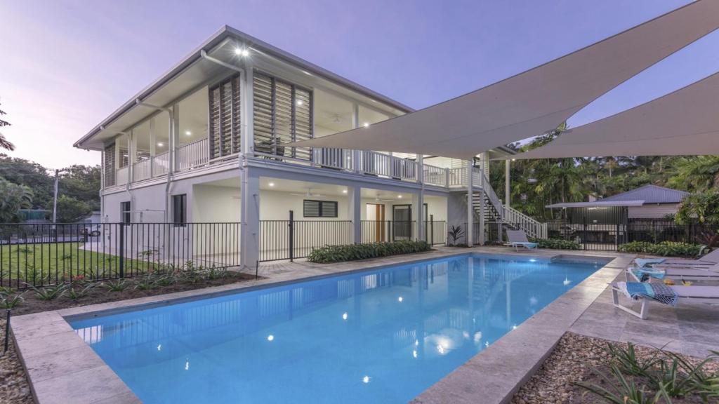 a home with a swimming pool in front of a house at Papaya Port Douglas in Port Douglas