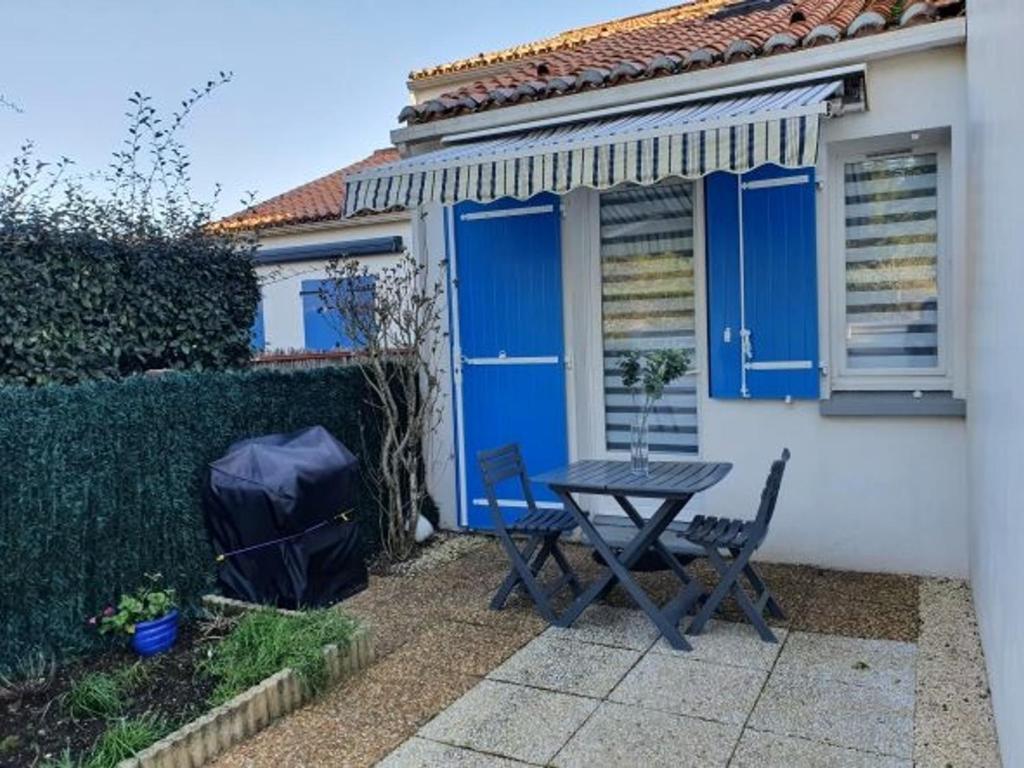 une table et des chaises devant une maison avec volets bleus dans l'établissement Maison La Faute-sur-Mer, 2 pièces, 4 personnes - FR-1-476-184, à La Faute-sur-Mer