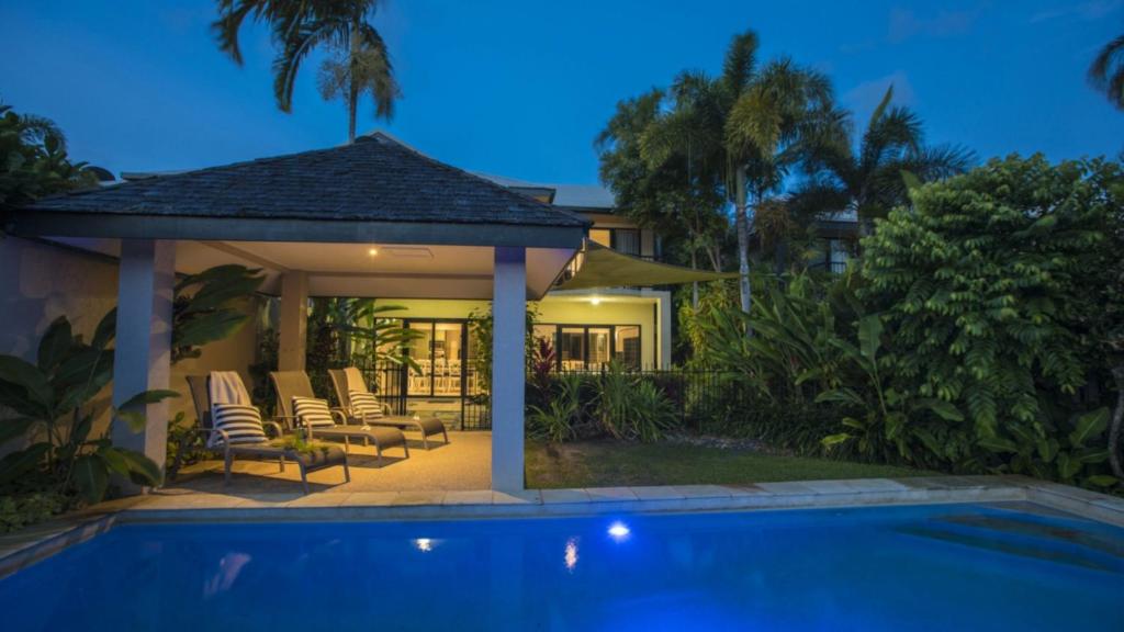 a villa with a swimming pool at night at Catalina Port Douglas in Port Douglas