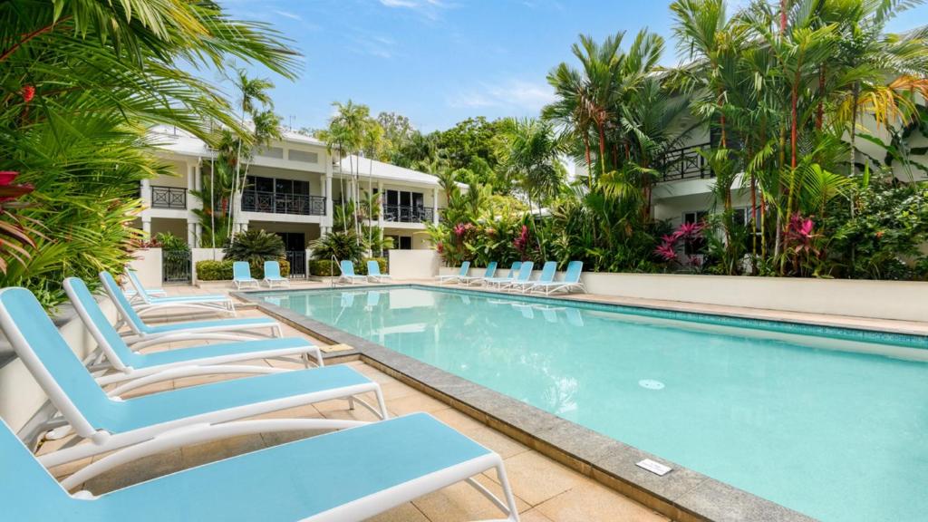 uma piscina com espreguiçadeiras em frente a um edifício em 9 Plantation House Port Douglas em Port Douglas