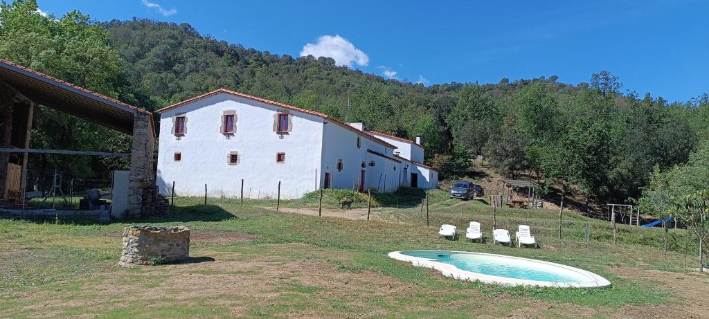 una fattoria con una piscina in erba accanto a un edificio di Mas Can Puig de Fuirosos a Barcellona