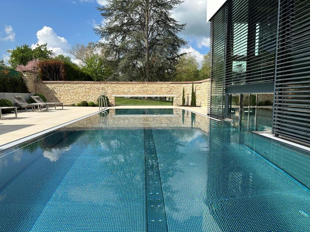 a swimming pool in front of a house at Auberge Saint Walfrid Hôtel Restaurant & Spa in Sarreguemines