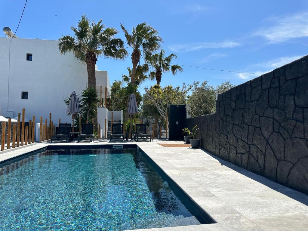 a swimming pool with a stone wall next to a house at Dragonfly Villas in Kamari