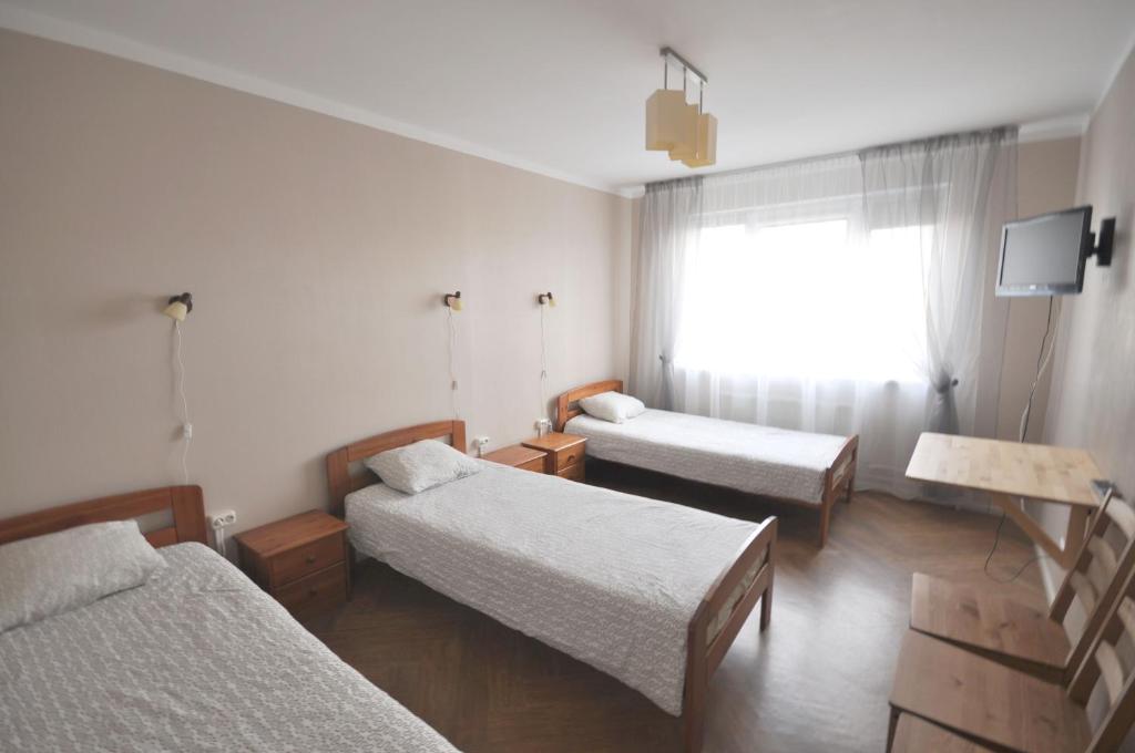a room with three beds and a window at Apartamenti Jēkabpilī in Jēkabpils
