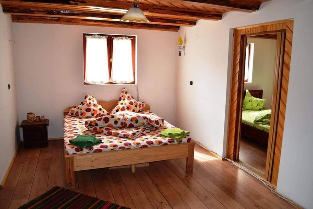 1 dormitorio con cama con almohadas y espejo en Cabană de munte la Voineasa, Vălcea, en Voineasa