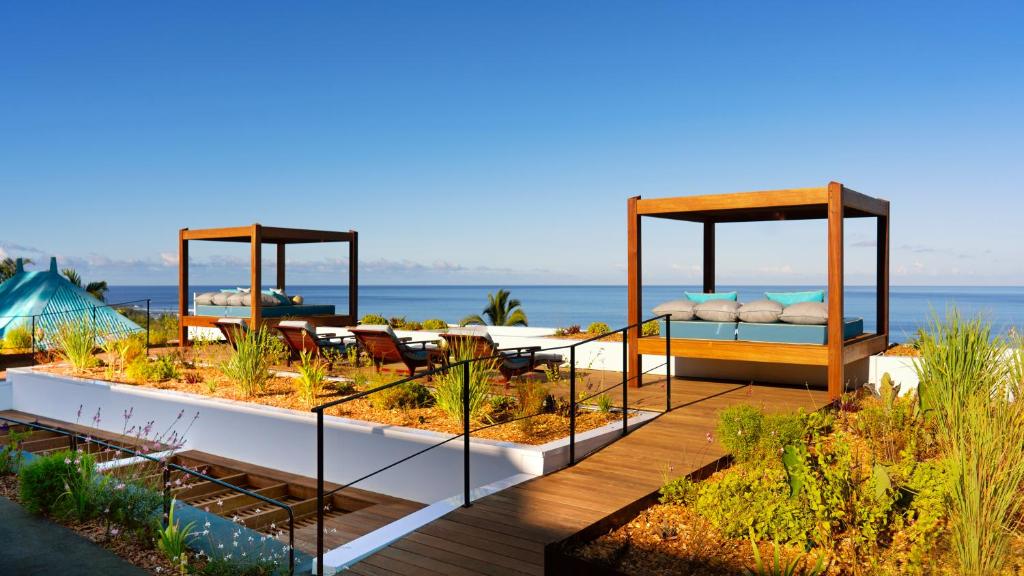 une terrasse avec un jardin doté de lits et de chaises dans l'établissement Blue Margouillat Seaview Hotel-RELAIS & CHATEAUX, à Saint-Leu