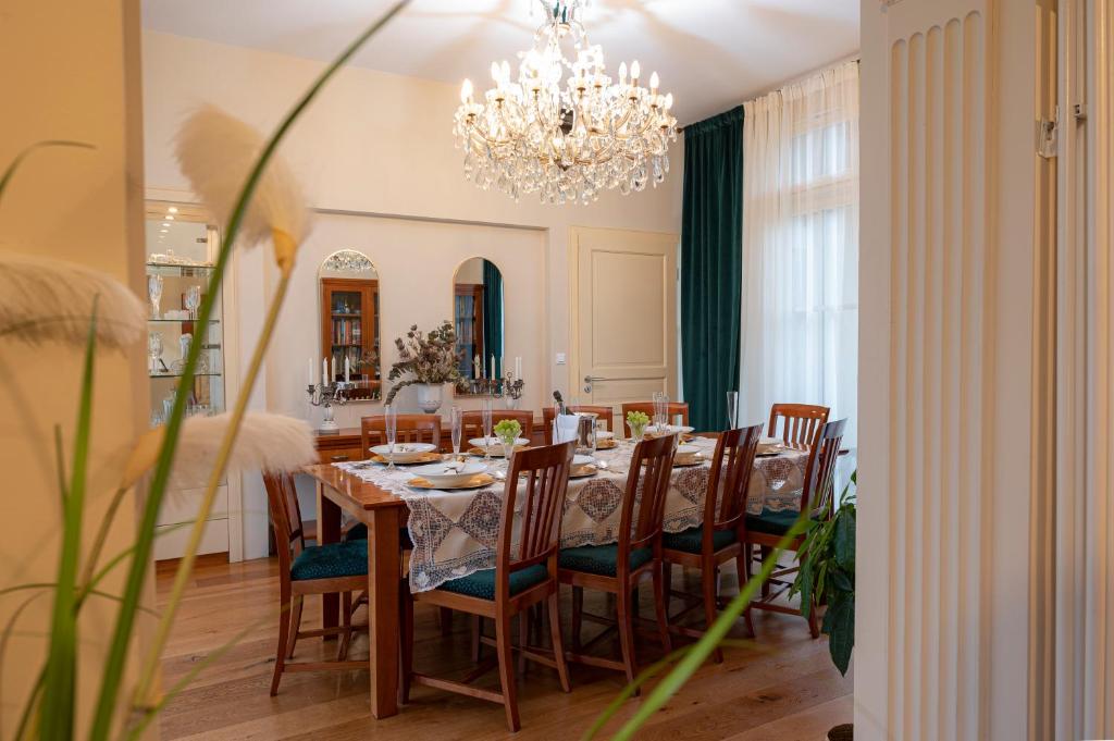 een eetkamer met een tafel en stoelen en een kroonluchter bij Villa Rory in Bled