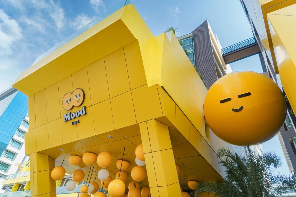 un bâtiment jaune avec une boule orange devant lui dans l'établissement Mood Hotel Pattaya, à Pattaya