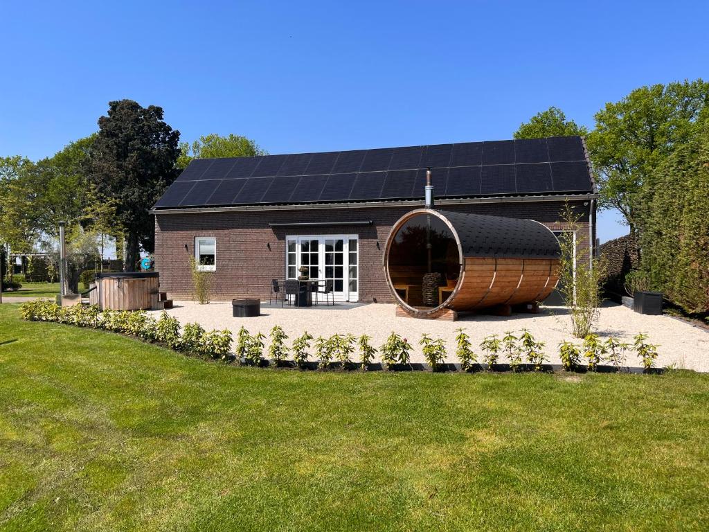 een huis met een zonnedak en een tuin bij Bed en wellness de Heyde in Veghel