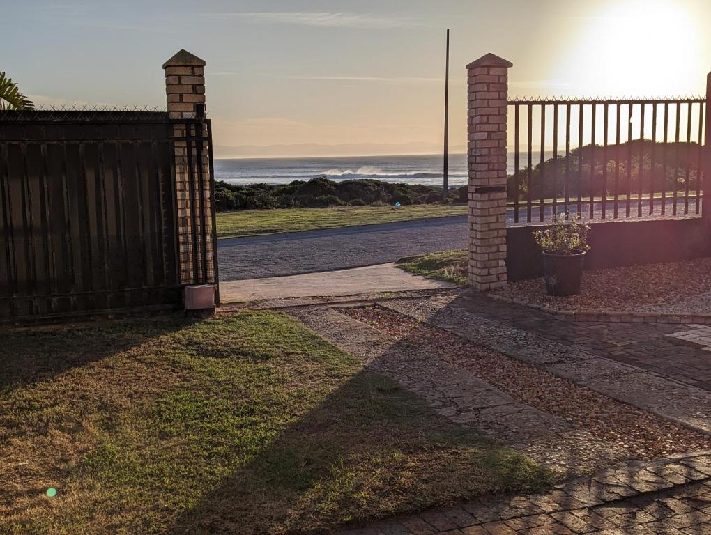 a gate to a driveway with the ocean in the background at @Kitchens in Jeffreys Bay
