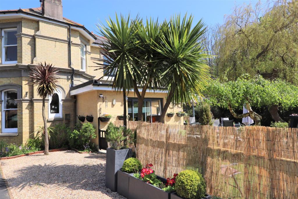 a house with a fence and a palm tree at Foxhills of Shanklin in Shanklin
