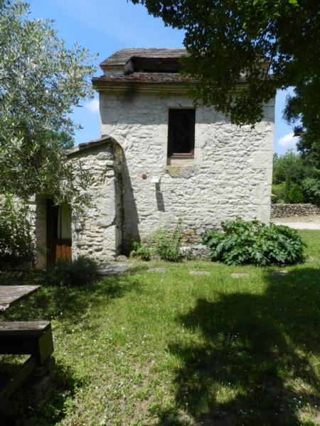 um antigo edifício de pedra com uma janela e um jardim de relva em gîtes de Combelcau, le Pigeonnier em Flaugnac