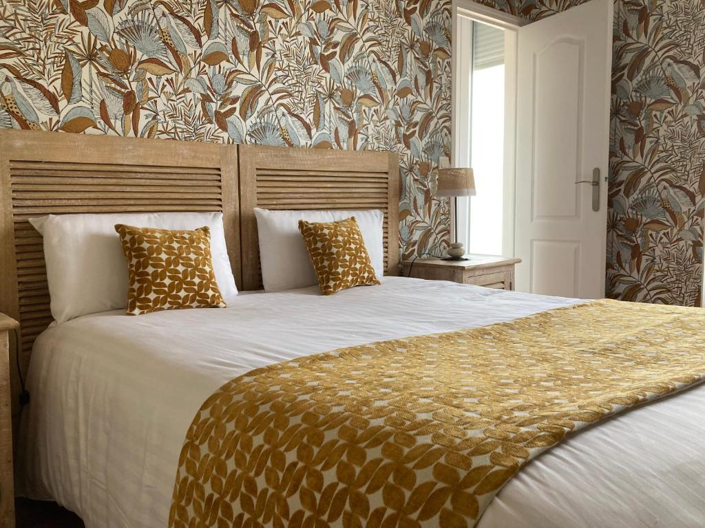 a bedroom with a large bed with gold pillows at Hotel Mona Lisa in La Baule