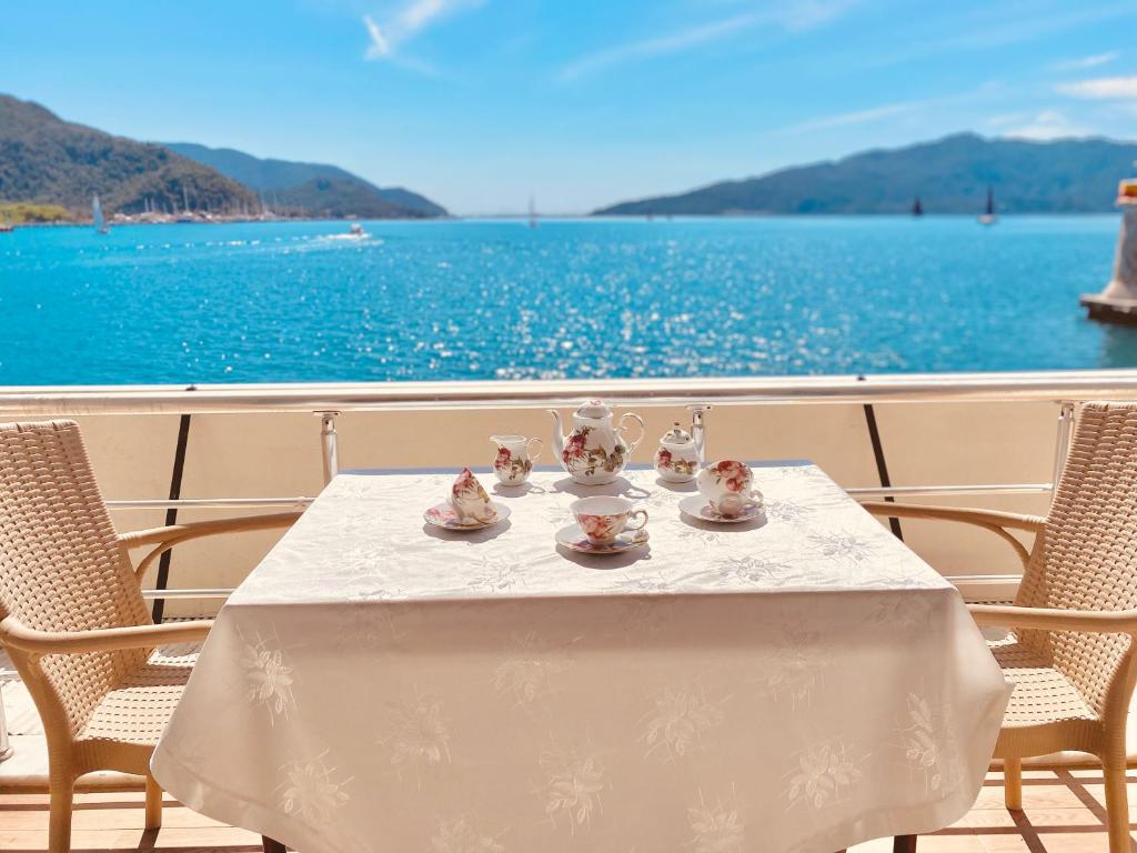 a table with cups and saucers on a balcony with the water at Port Mansion in Marmaris