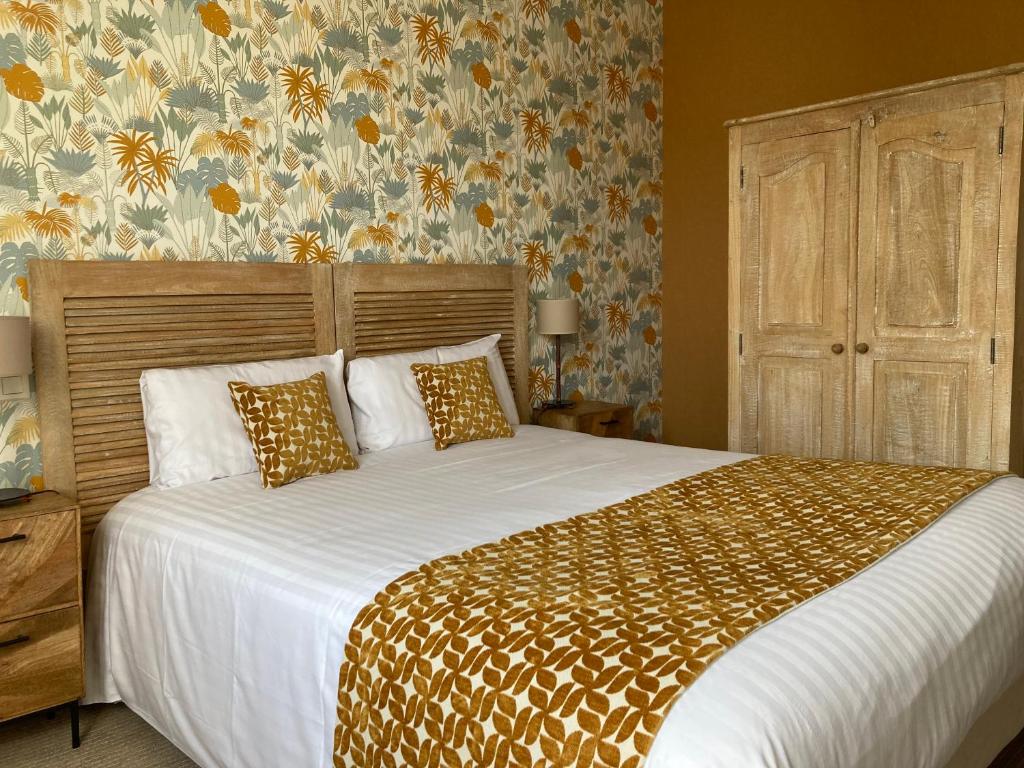 a bedroom with a large bed with white sheets and floral wallpaper at Hotel Mona Lisa in La Baule