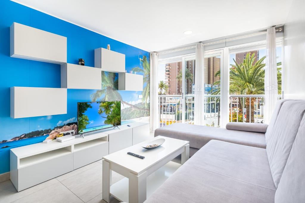 ein Wohnzimmer mit einem weißen Sofa und einem TV in der Unterkunft Seimar 1-8 Apartment Levante Beach in Benidorm