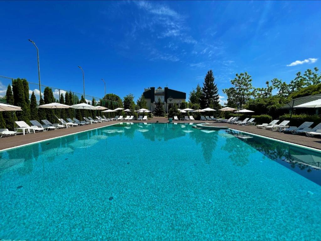 a large blue swimming pool with chairs and umbrellas at Platium Spa&Resort in Kozin