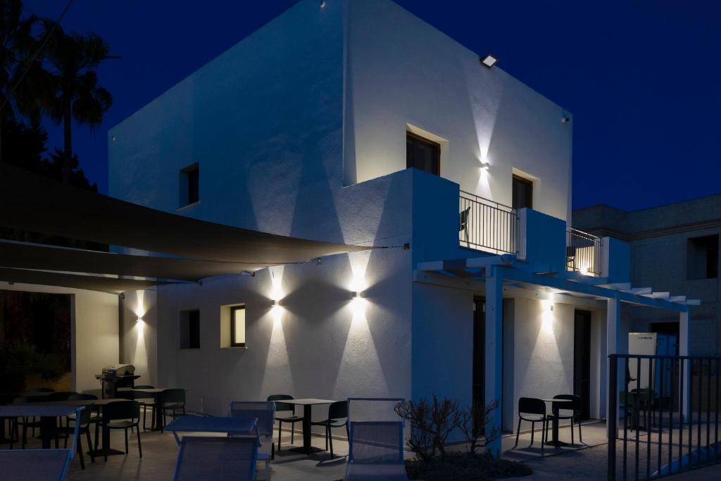 een wit gebouw met 's nachts tafels en stoelen bij Casa B, Room 6 - Palm Kite Paradise in Marsala
