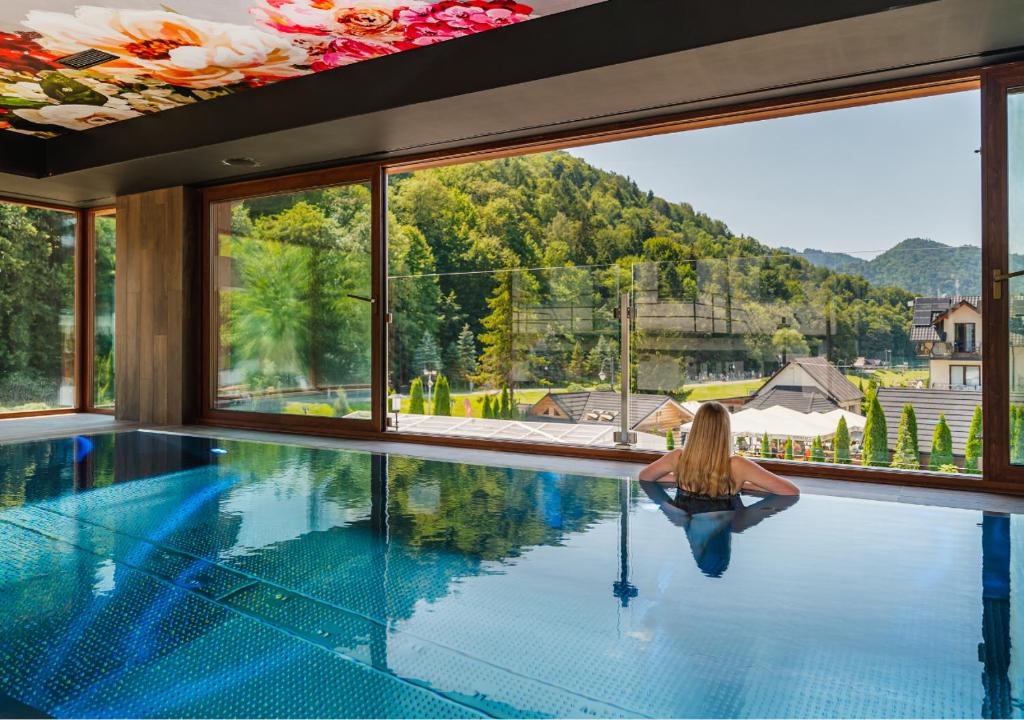 Eine Frau, die in einem Schwimmbad in einem Haus sitzt. in der Unterkunft Szczawnica Park Resort & Spa in Szczawnica