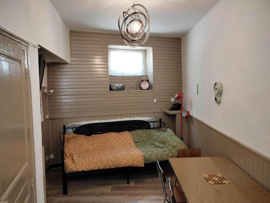 une petite chambre avec un lit et une table dans l'établissement Le nid douillet Vintage, à La Bourboule