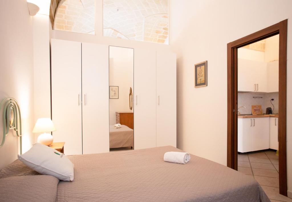a bedroom with a bed with a mirror and a kitchen at Casetta Diana - The Fab Stay in Brindisi