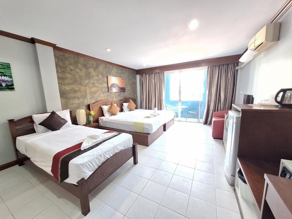 カタビーチにあるSea Boss Homestayのベッド2台とテレビが備わるホテルルームです。