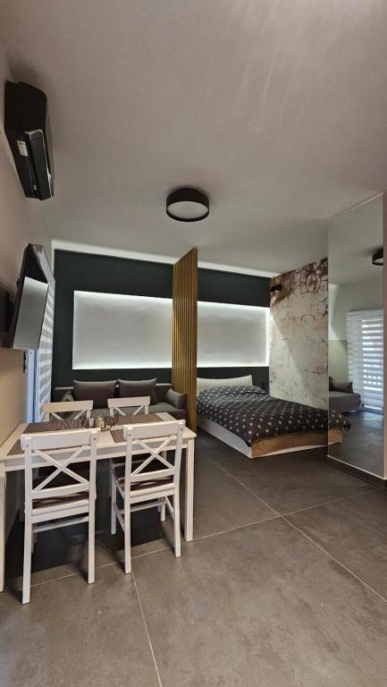 ein Wohnzimmer mit einem Tisch, Stühlen und einem Bett in der Unterkunft TheNik_Studio in Nafpaktos