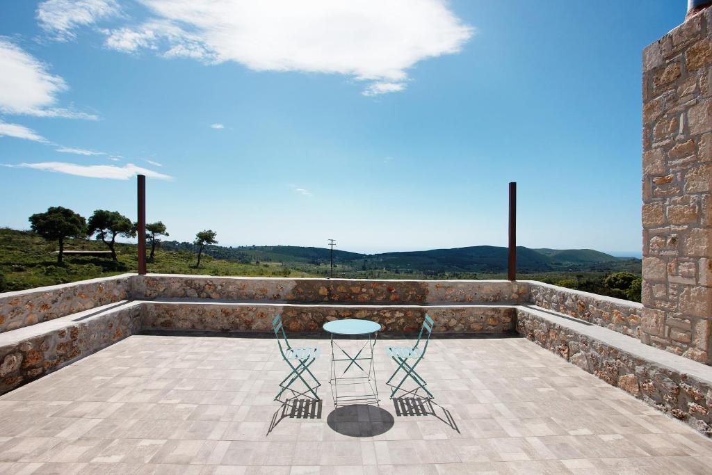 a patio with a table and chairs on a stone wall at Wild Fig Retreat Thalassa and Loft in Maryiés