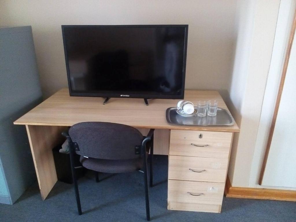 Habitación con escritorio, TV y silla. en Neat guest suite with office corner - 2101 en Harare