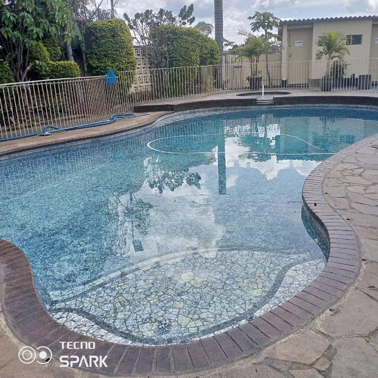 una piscina de agua azul en un patio en Neat and cosy cottage with pool - 2103 en Harare