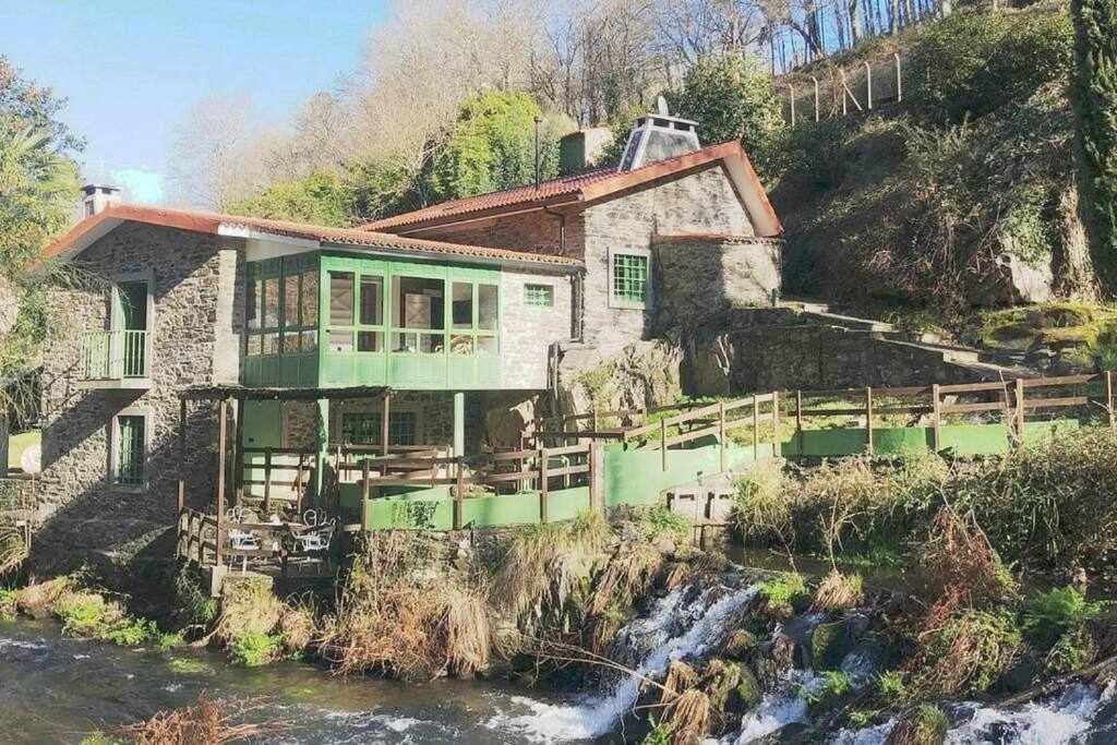 een huis op een heuvel naast een rivier bij Molino verde in Coirós